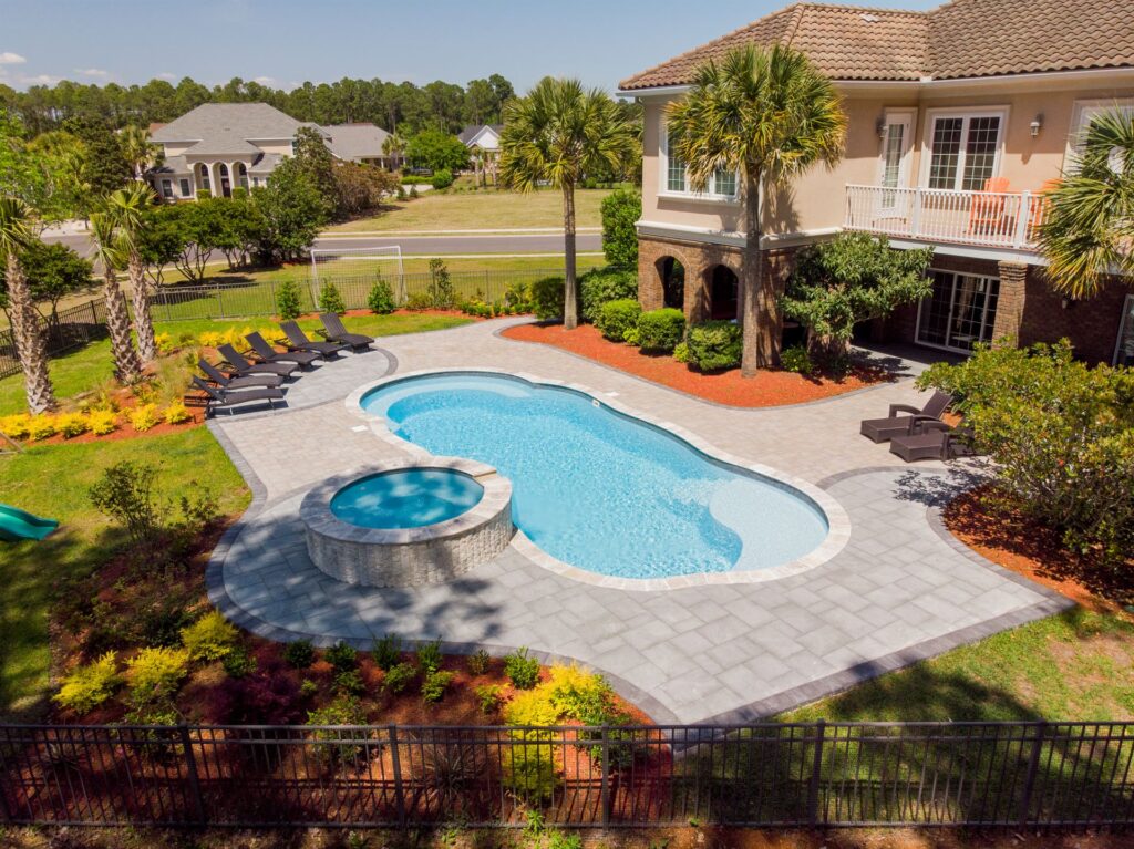 002. River Pools C40 + RS08 with spillway in Caribbean Sparkle with concrete paver patio and natural stone coping