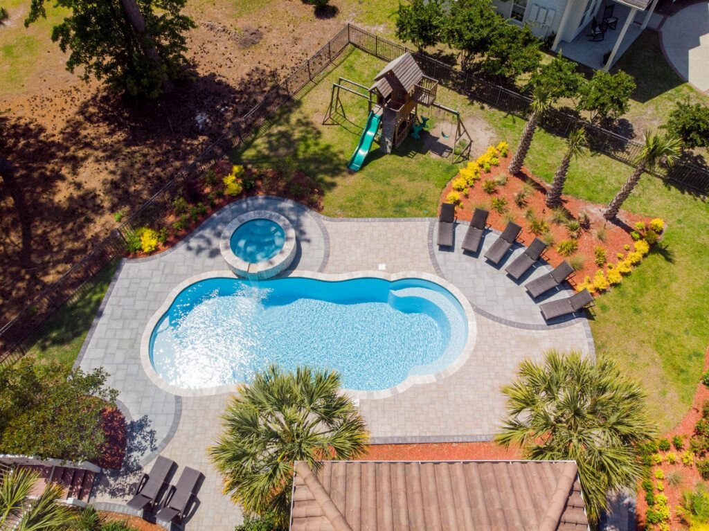 007. River Pools C40 + RS08 with spillway in Caribbean Sparkle with concrete paver patio and natural stone coping