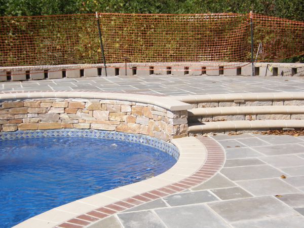 A professionally designed patio encircling a fiberglass swimming pool. The coping, made from high-quality stone or paver materials, adds a touch of sophistication as it gracefully crowns the pool's edge. The patio, built with meticulous craftsmanship, offers a spacious and inviting space for relaxation and entertainment.